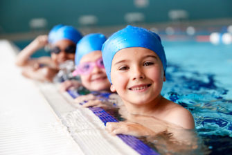portrait-of-children-in-water-at-edge-of-pool-waiting-for-swimming-lesson